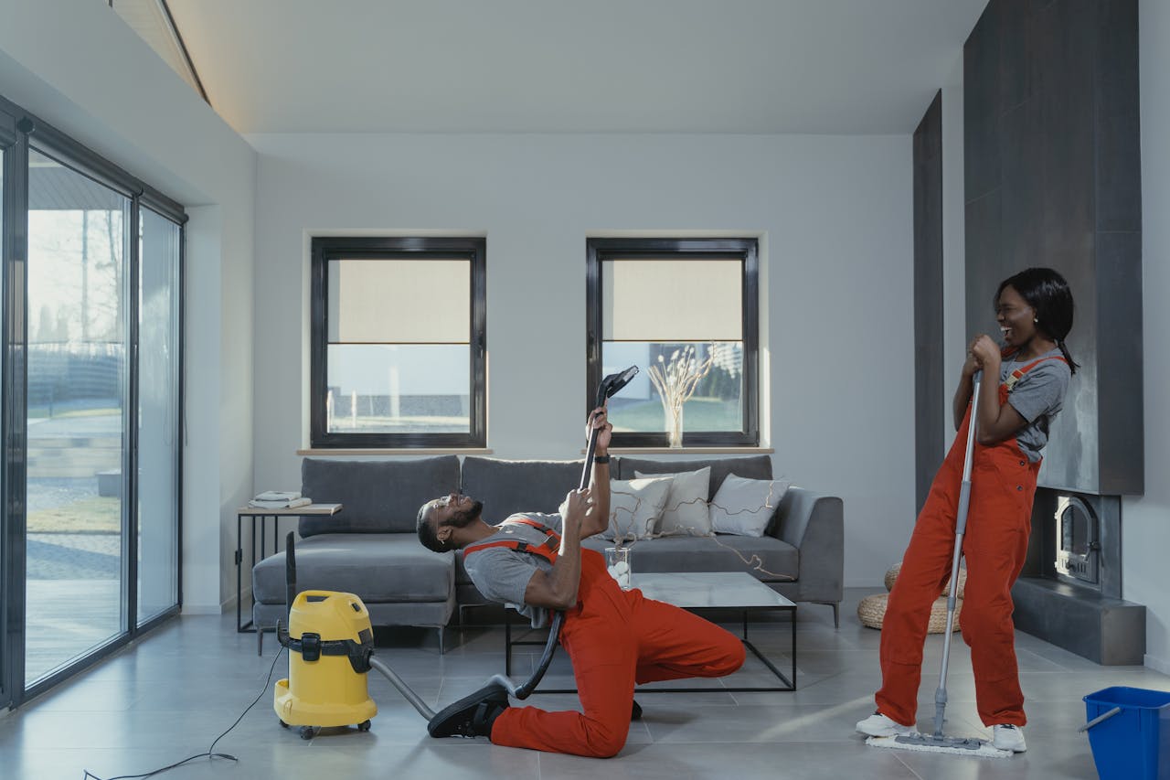 about-01 Fun and engaging cleaning session with a man and woman in overalls using cleaning tools in a modern living room.